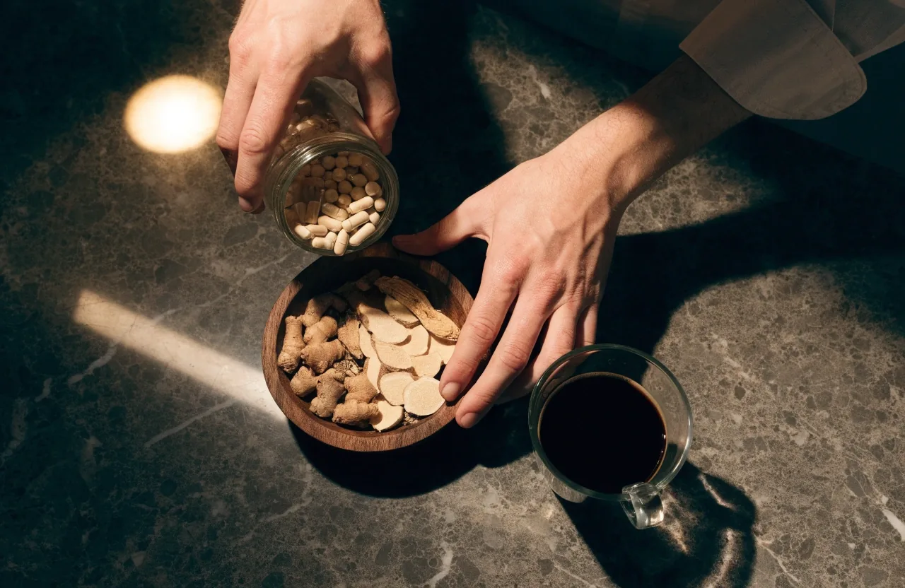 Mains versant des gélules d'un pot en verre ambré sur une surface de pierre sombre