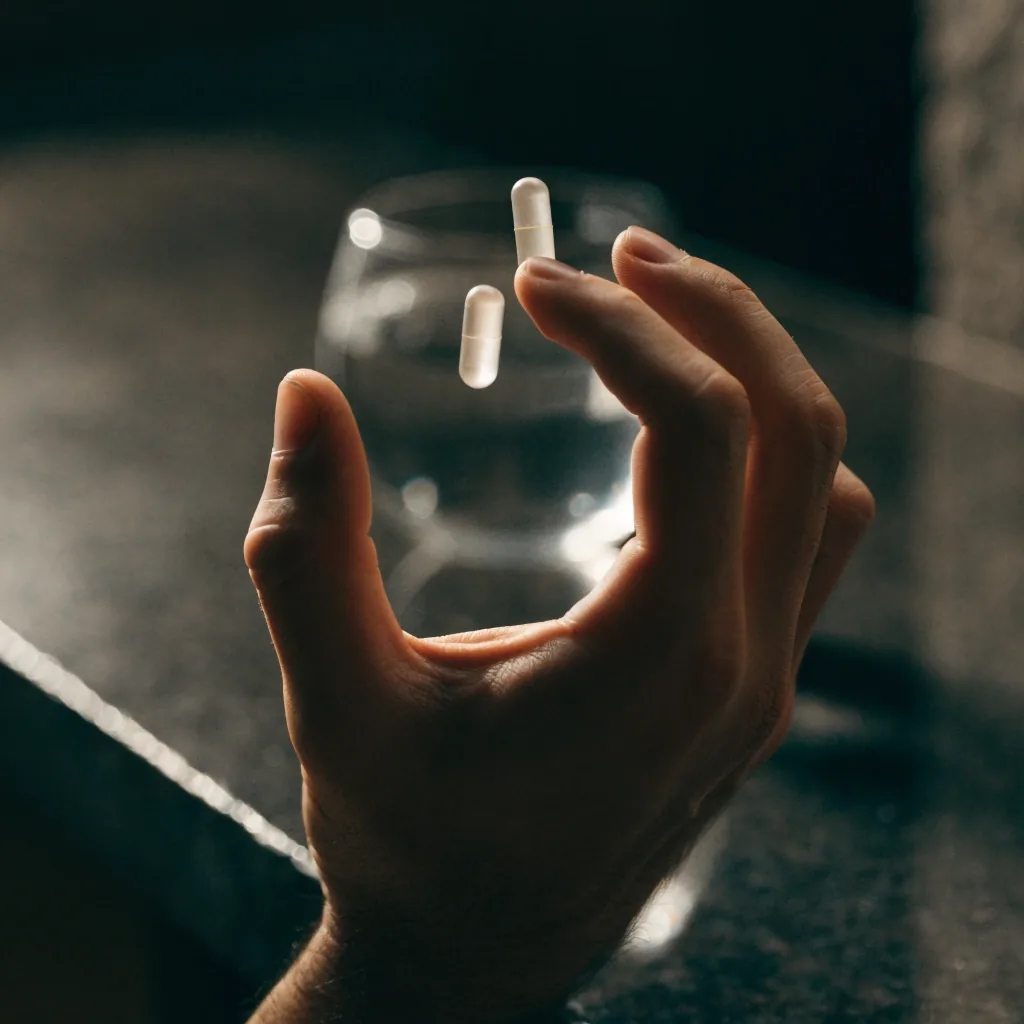 Une capsule pâle posée sur une surface de pierre sombre, presque entièrement dans l'ombre